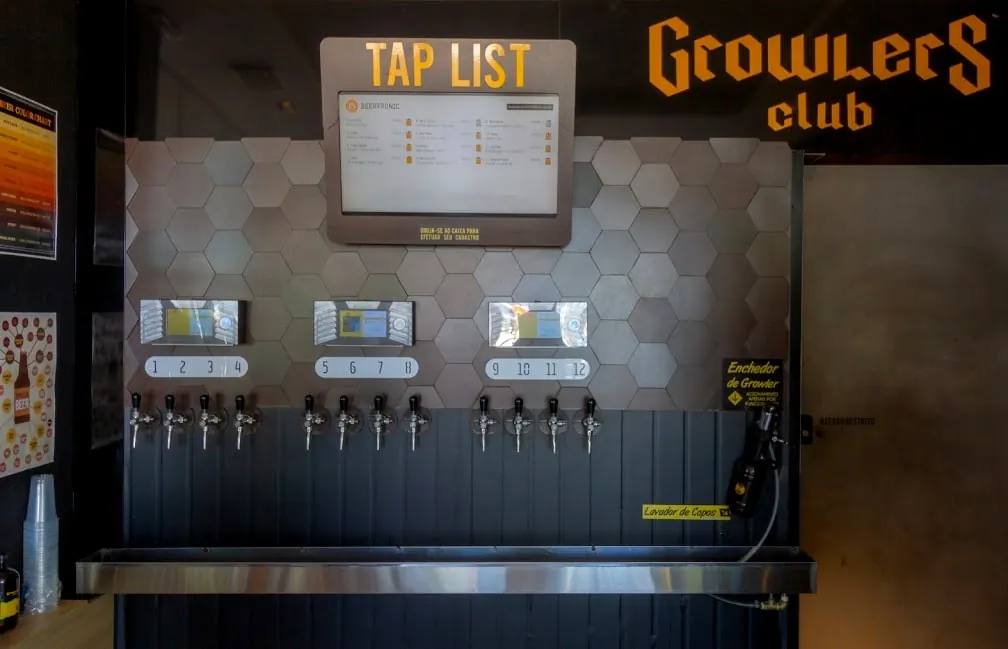 Parede de torneiras com máquinas Beertronic e painel de tap list no Growlers Club Biergarten